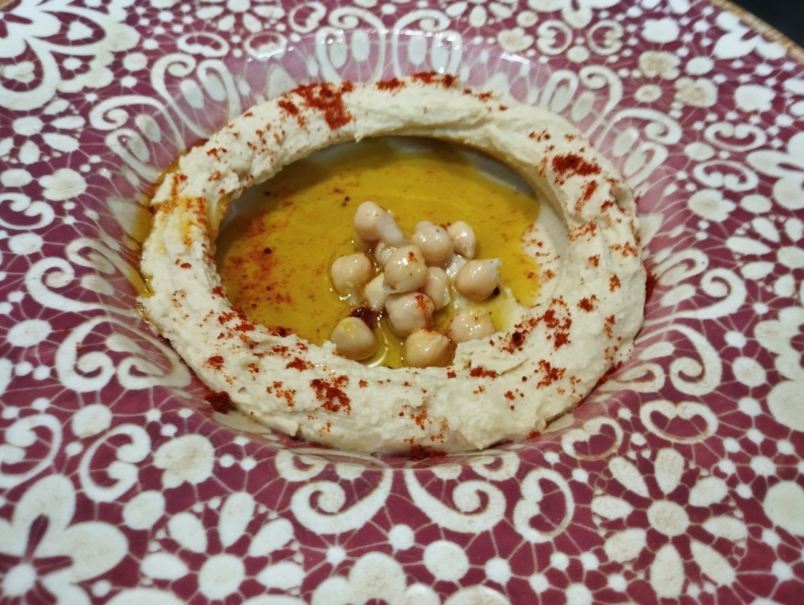 Hummus with olive oil, chickpeas and paprika on a patterned plate