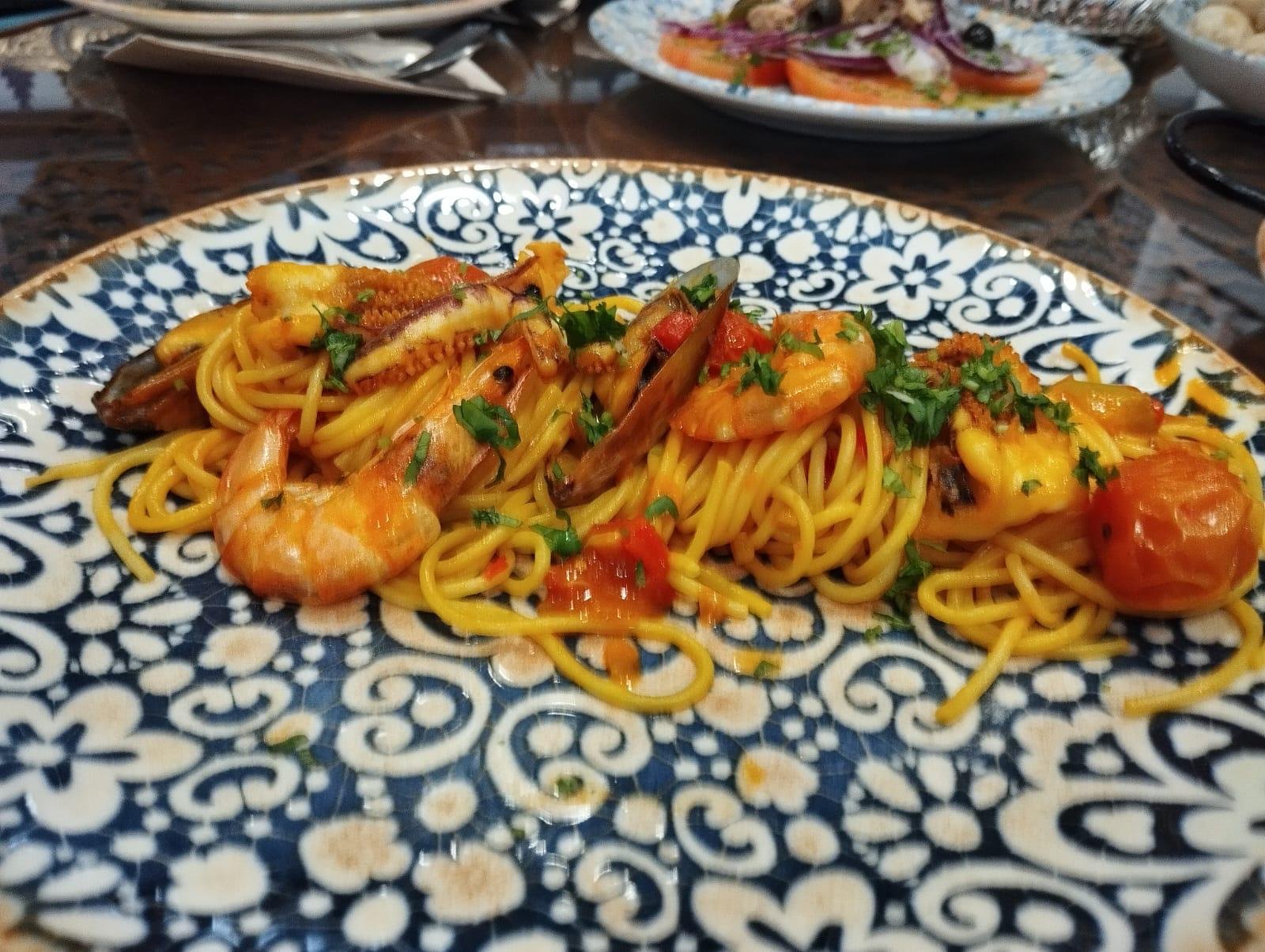 Spaghetti with prawns and tomato on a patterned plate