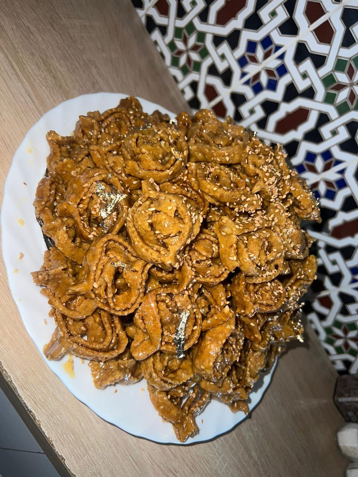Plate of chebakia pastries in front of a zellige tiled wall